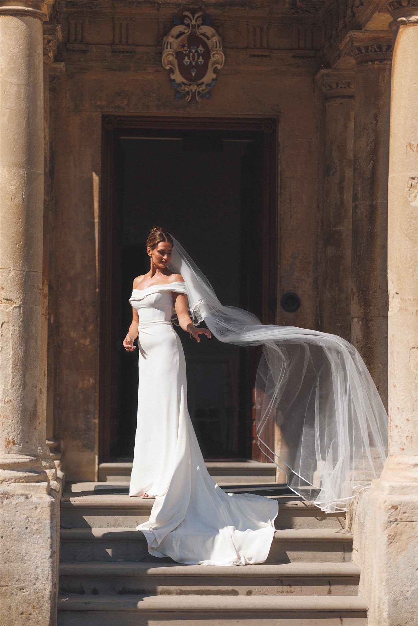 Zofia on the stone steps at Elmore Court, her veil catching the light
