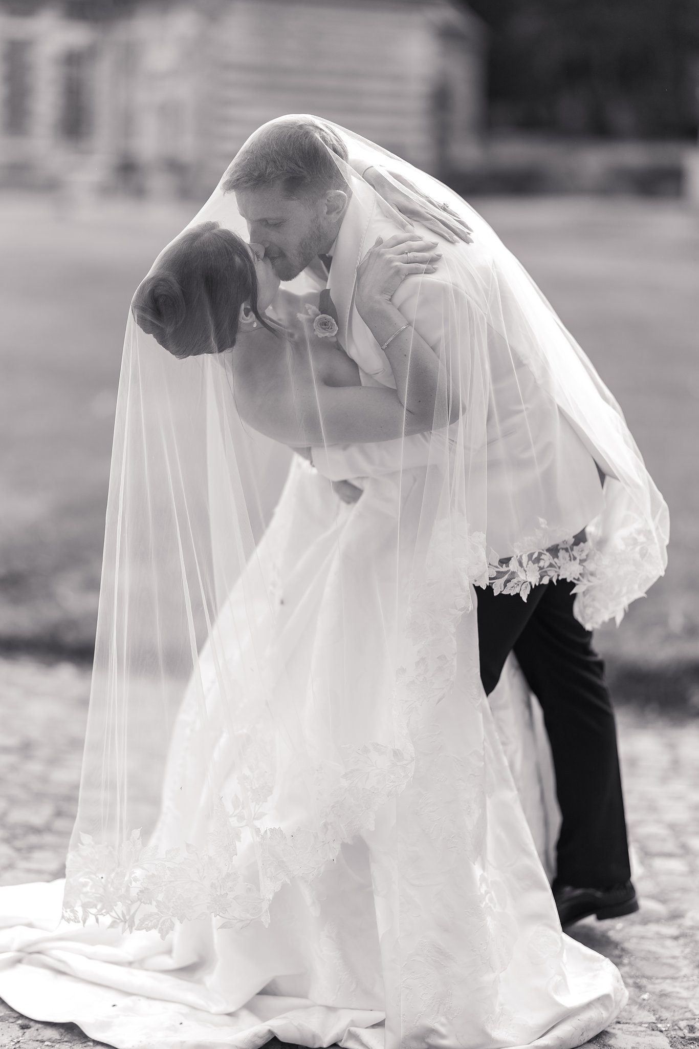 A couple kissing beneath the bride’s veil, in black and white