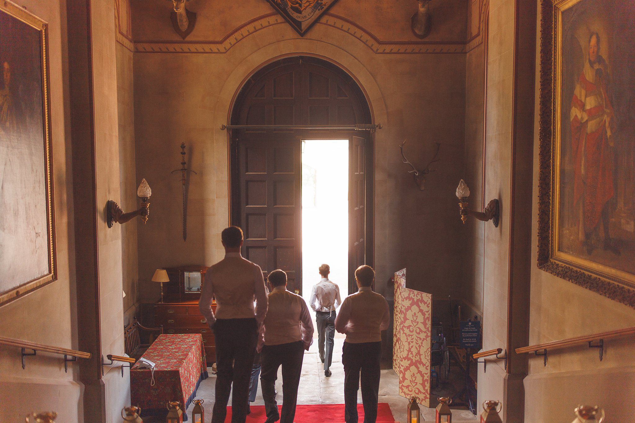 The groomsmen walking down the long hall at Eastnor Castle